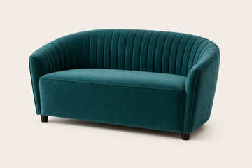 A modern curved loveseat sofa upholstered in deep teal velvet with vertical channel tufting on the backrest, shown against a plain light beige background.