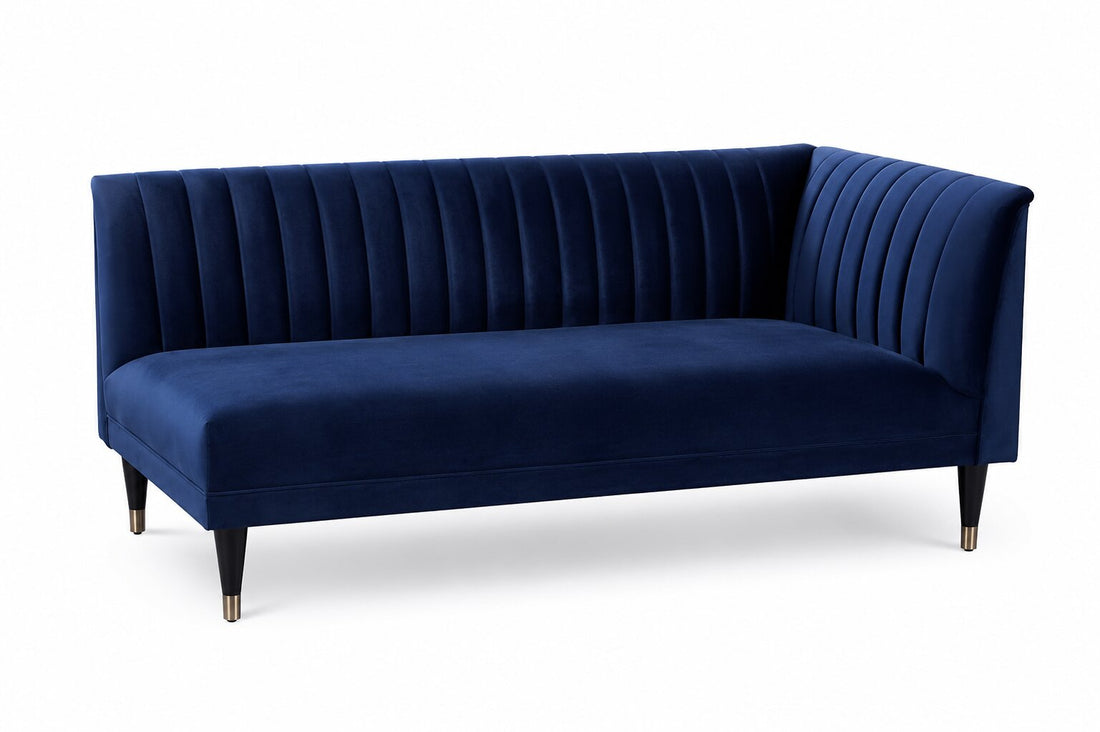 A modern gray velvet corner sofa with vertical channel tufting on the backrest and arms, supported by black tapered legs with gold caps, shown on a white background.