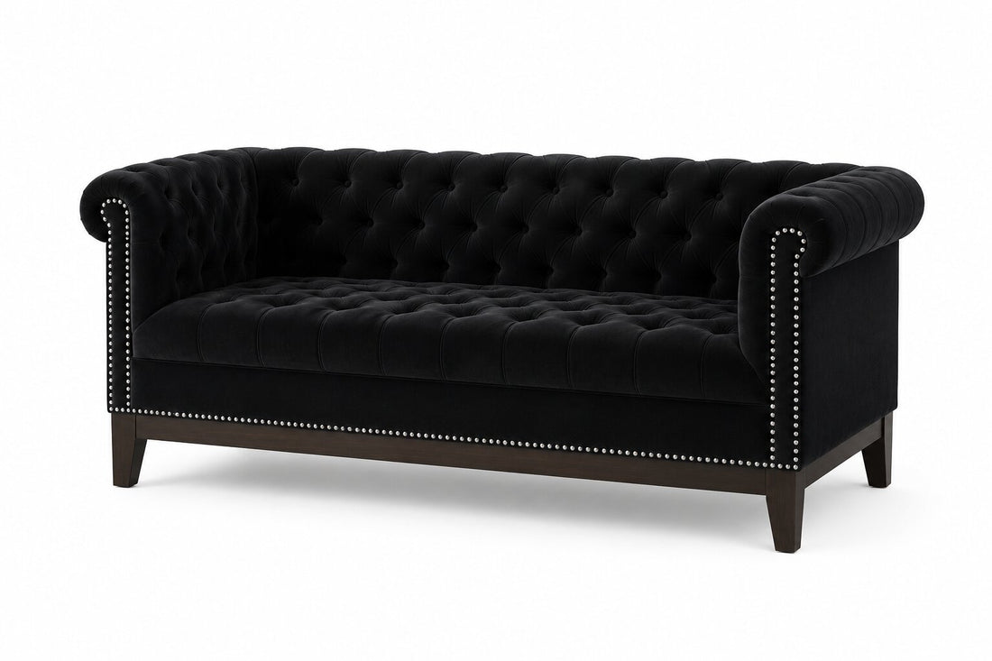 A classic Chesterfield loveseat sofa upholstered in deep navy blue velvet, featuring tufted button detailing, rolled arms, silver nailhead trim, and dark brown wooden legs, shown against a plain white background.