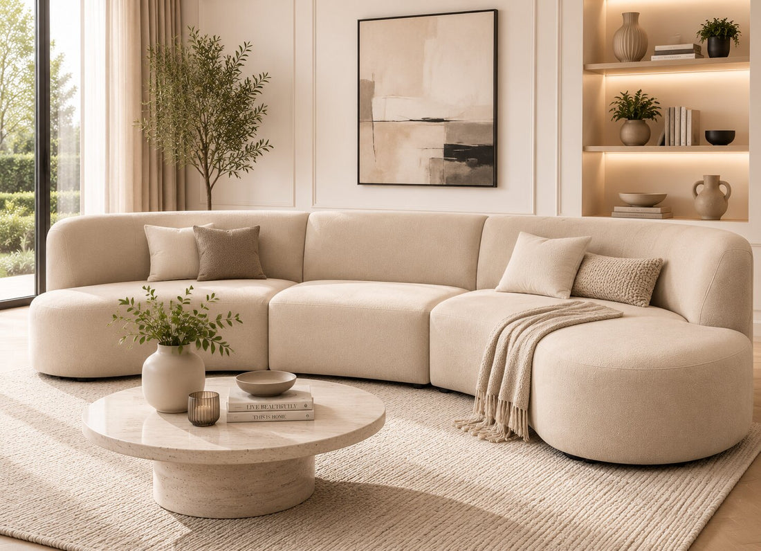 A curved modular upholstered sofa in a light beige fabric, shown from a front three-quarter angle against a plain white background.