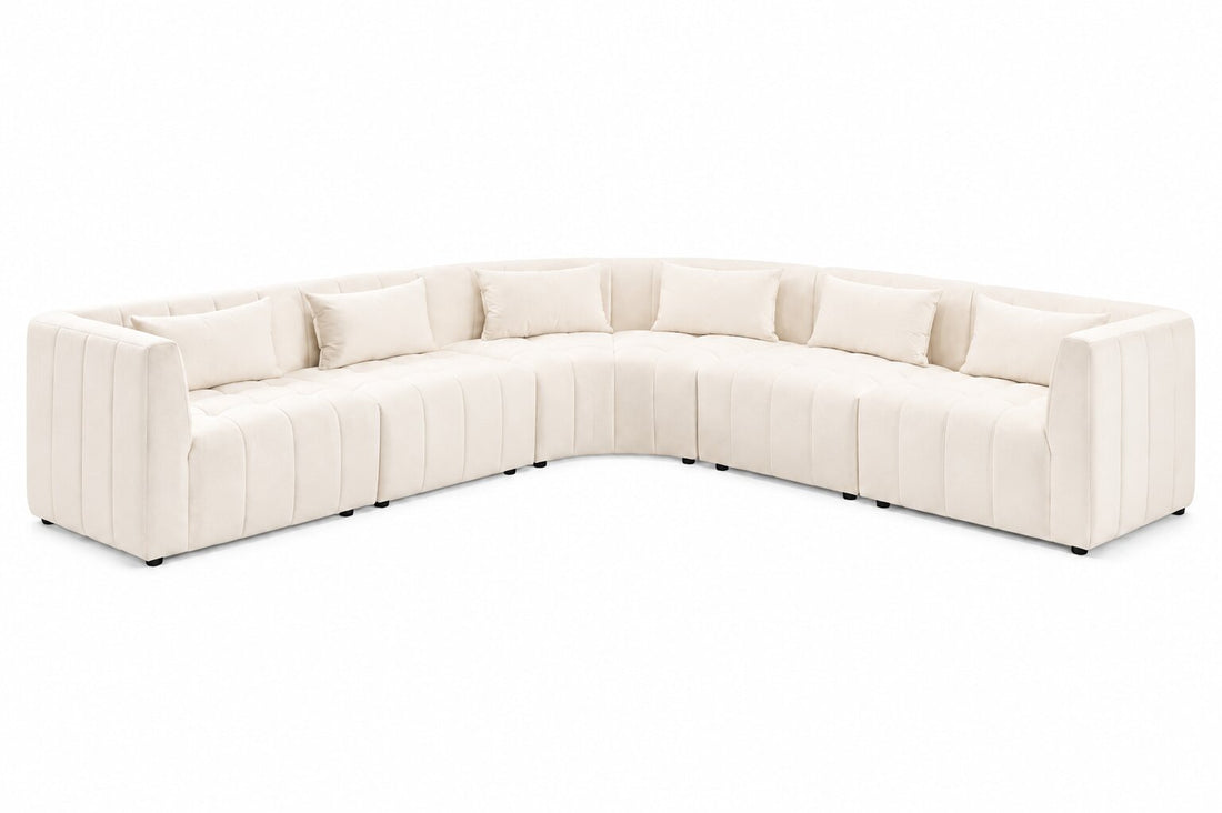 A curved modular sectional sofa upholstered in cream-colored fabric with vertical channel tufting and matching throw pillows, shown on a plain white background.