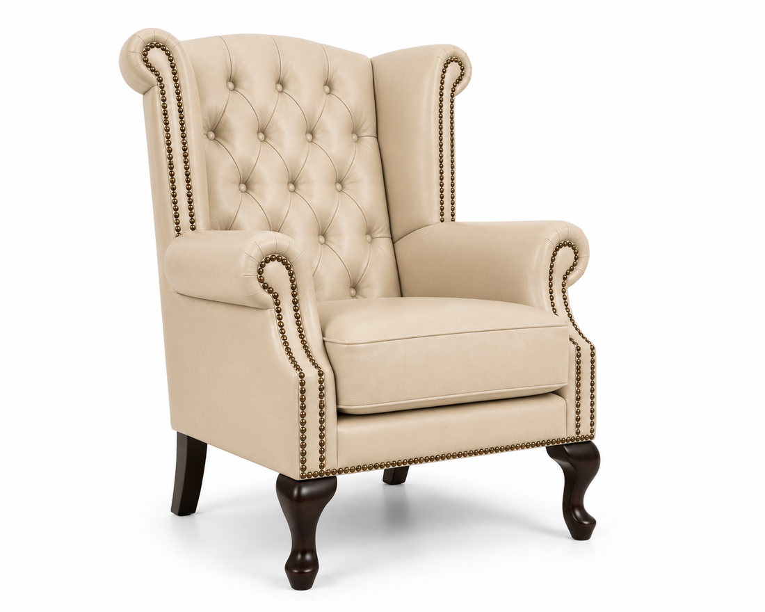 A classic wingback armchair upholstered in beige tufted fabric with dark brown wooden legs and brass nailhead trim, shown on a white background.