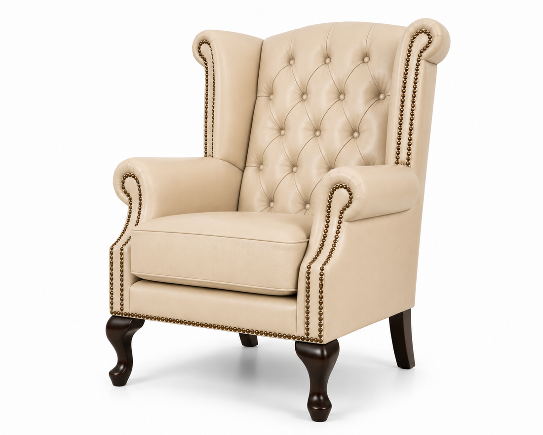 A classic wingback armchair upholstered in beige tufted fabric with dark brown wooden legs and brass nailhead trim, shown on a white background.